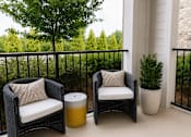 Thumbnail 10 of 30 - Covered balcony with wicker seating and greenery at The Crest at Acworth Apartments, Georgia, 30102