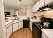 Thumbnail 12 of 40 - A kitchen with black appliances and white cabinets.