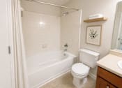 Thumbnail 24 of 40 - A white bathroom with a toilet, sink, and bathtub.