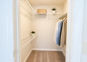 Thumbnail 21 of 40 - A white closet with clothes hanging and a plant on the shelf.