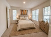Thumbnail 9 of 40 - A bedroom with a large bed, a dresser, and a painting on the wall.
