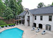 Thumbnail 3 of 40 - A pool and loungers in front of a white building with a black roof.