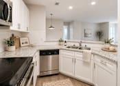 Thumbnail 5 of 40 - A modern kitchen with white cabinets and stainless steel appliances.