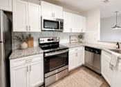 Thumbnail 4 of 40 - A kitchen with white cabinets and stainless steel appliances.