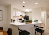 Thumbnail 13 of 40 - A kitchen with a white countertop and black chairs.