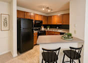 Thumbnail 18 of 40 - A kitchen with black chairs and a black refrigerator.
