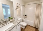Thumbnail 11 of 40 - A bathroom with a white toilet, a sink, a bathtub, and a shower.