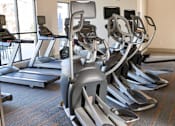 Thumbnail 15 of 27 - a row of exercise machines in a gym at The Crest at Laurel Canyon Apartments, Canton