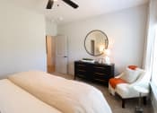 Thumbnail 10 of 60 - a bedroom with a large bed and a chair and a dresser with a mirror at The Crest at South Point Apartments, McDonough, GA