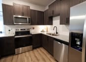 Thumbnail 4 of 60 - a kitchen with stainless steel appliances and dark wood cabinets at The Crest at South Point Apartments, McDonough