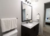 Thumbnail 14 of 60 - a bathroom with a sink and a mirror and a toilet at The Crest at South Point Apartments, McDonough, Georgia