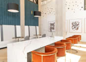 Thumbnail 22 of 46 - a communal table with orange chairs and a marble counter top in a restaurant at The Wren Apartments, Georgia, 30043