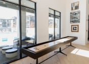 Thumbnail 26 of 46 - a shuffleboard table in a room with large windows at The Wren Apartments, Lawrenceville, GA