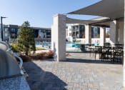 Thumbnail 19 of 46 - a patio with tables and chairs and a swimming pool at The Wren Apartments, Lawrenceville, GA, 30043