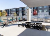 Thumbnail 18 of 46 - an outdoor patio with tables and chairs at an apartment building at The Wren Apartments, Georgia, 30043