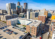 Thumbnail 1 of 8 - A cityscape with a large building in the foreground and several other buildings in the background.