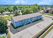 Thumbnail 6 of 13 - A large blue building with a parking lot in front of it.