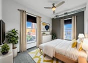 Thumbnail 6 of 8 - A bedroom with a large bed, a ceiling fan, and a view of a cityscape through the windows.