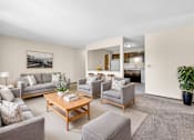 Thumbnail 8 of 13 - A living room with a grey couch, a grey armchair, a grey ottoman, a wooden coffee table, a potted plant, and a framed picture on the wall.