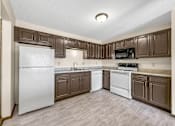 Thumbnail 10 of 13 - A kitchen with brown cabinets and a white refrigerator.