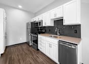 Thumbnail 7 of 11 - A kitchen with white cabinets and a black refrigerator.