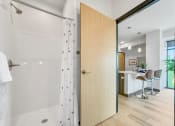 Thumbnail 17 of 18 - an open bathroom door leading to a shower with a curtain