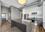 Thumbnail 4 of 8 - A modern kitchen with a wooden island and stainless steel appliances.