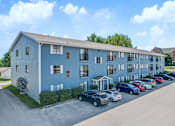 Thumbnail 2 of 13 - A blue building with cars parked in front.