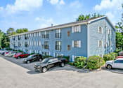 Thumbnail 3 of 13 - A blue building with a parking lot in front of it.