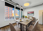 Thumbnail 5 of 8 - A dining room with a table set for four and a view of a cityscape through the windows.