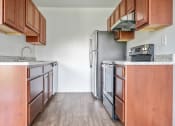 Thumbnail 8 of 14 - an empty kitchen with wooden cabinets and a stainless steel refrigerator