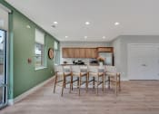 Thumbnail 3 of 48 - a kitchen with a long bar with chairs and a green wall