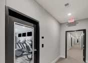 Thumbnail 6 of 48 - a hallway with a door to a gym with a mirror on the wall