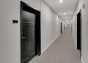 Thumbnail 11 of 48 - a hallway with black doors and white walls and a carpeted floor