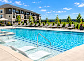 Thumbnail 26 of 37 - A swimming pool with lounge chairs and a building in the background.