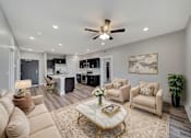 Thumbnail 12 of 48 - A living room with a beige sofa, a coffee table, and a ceiling fan.