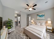 Thumbnail 14 of 48 - A bedroom with a large bed, a ceiling fan, and a painting on the wall.