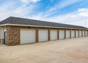Thumbnail 18 of 32 - A long building with a grey roof and white garage doors.