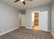Thumbnail 12 of 32 - A room with a ceiling fan and a carpeted floor.