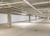 Thumbnail 17 of 32 - A large, empty parking garage with concrete floors and white walls.