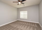 Thumbnail 9 of 32 - A room with a ceiling fan and carpeted floor.