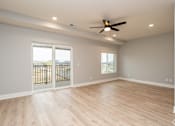 Thumbnail 15 of 32 - A room with a ceiling fan and sliding glass doors.
