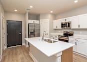 Thumbnail 1 of 32 - A modern kitchen with white countertops and stainless steel appliances.