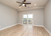 Thumbnail 2 of 32 - A room with a ceiling fan and sliding glass doors.