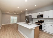 Thumbnail 8 of 32 - A kitchen with white cabinets and a wooden island.