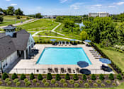Thumbnail 33 of 44 - A large swimming pool surrounded by a fence and a building in the background.