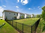 Thumbnail 7 of 44 - A black fence surrounds a grassy area in front of a row of houses.