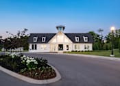 Thumbnail 3 of 44 - A white house with a black roof and a tower-like structure on the roof is surrounded by a garden with white flowers and a street lamp.