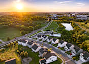 Thumbnail 23 of 44 - A sunset view of a residential area with houses and a park.