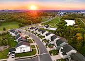Thumbnail 27 of 44 - A sunset view of a residential neighborhood with houses and a lake.